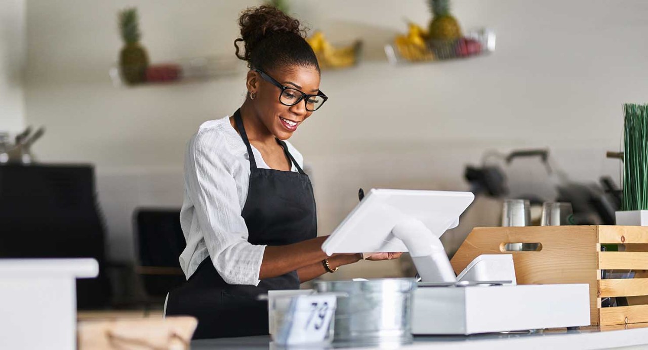 Friendly African American Shop owner Using Point of sale Terminal