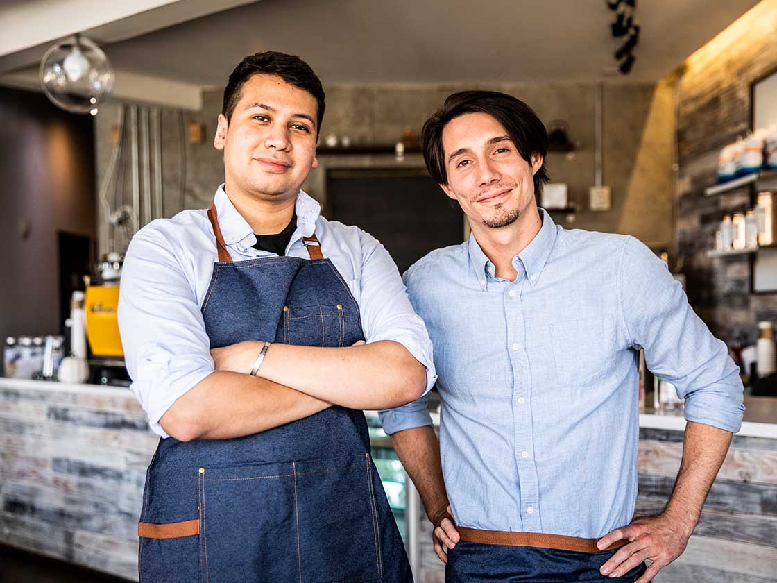 Two small business workers standing outside their cafe